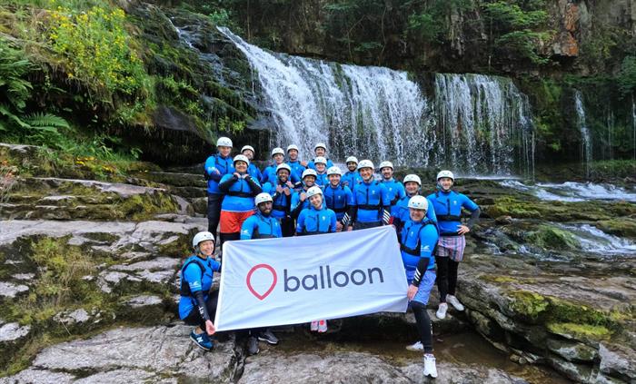 Balloon team holding logo banner during company offsite adventure activity canyoning in Wales